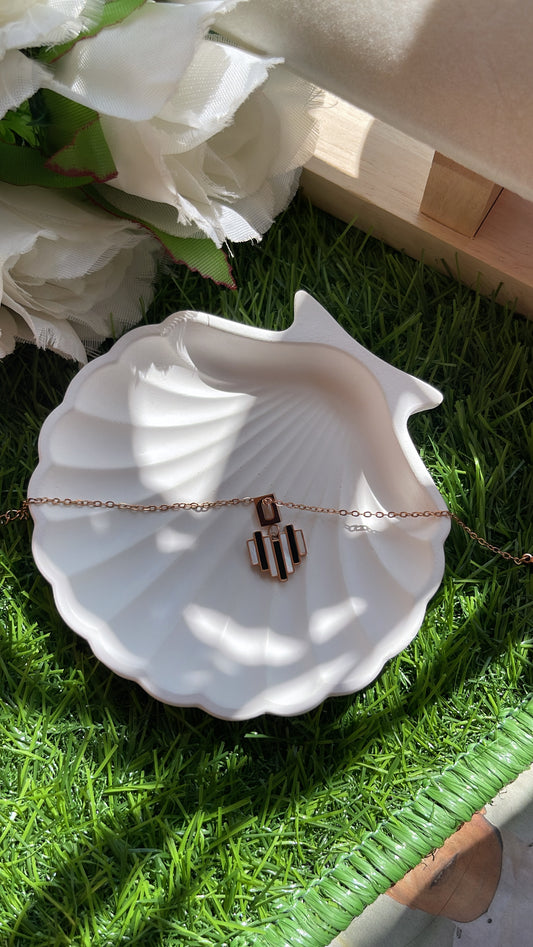 White shell-shaped dish with a rose gold bracelet on grass