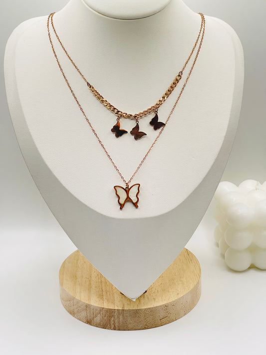 Butterfly-themed necklaces on a white mannequin bust with a wooden base.