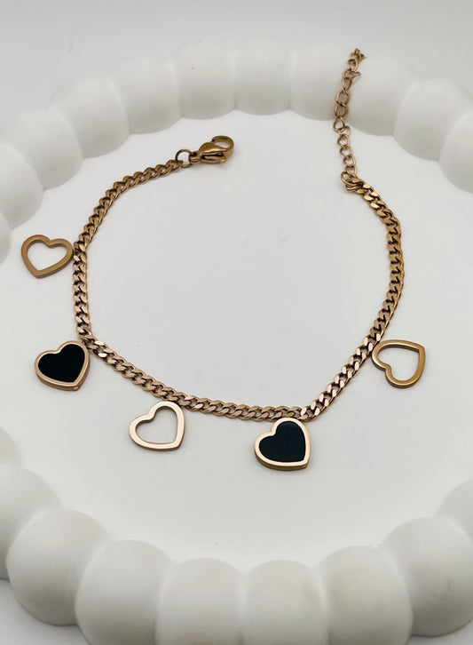 Rose Gold bracelet with heart-shaped charms on a white textured surface