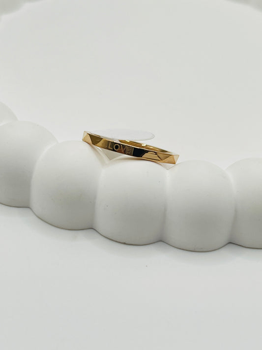 Rose Gold bracelet with 'LOVE' engraving on a white ceramic dish