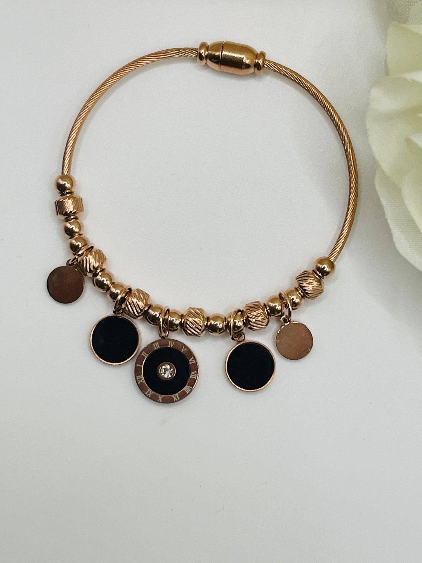 Rose Gold bracelet with black round charms on a white background