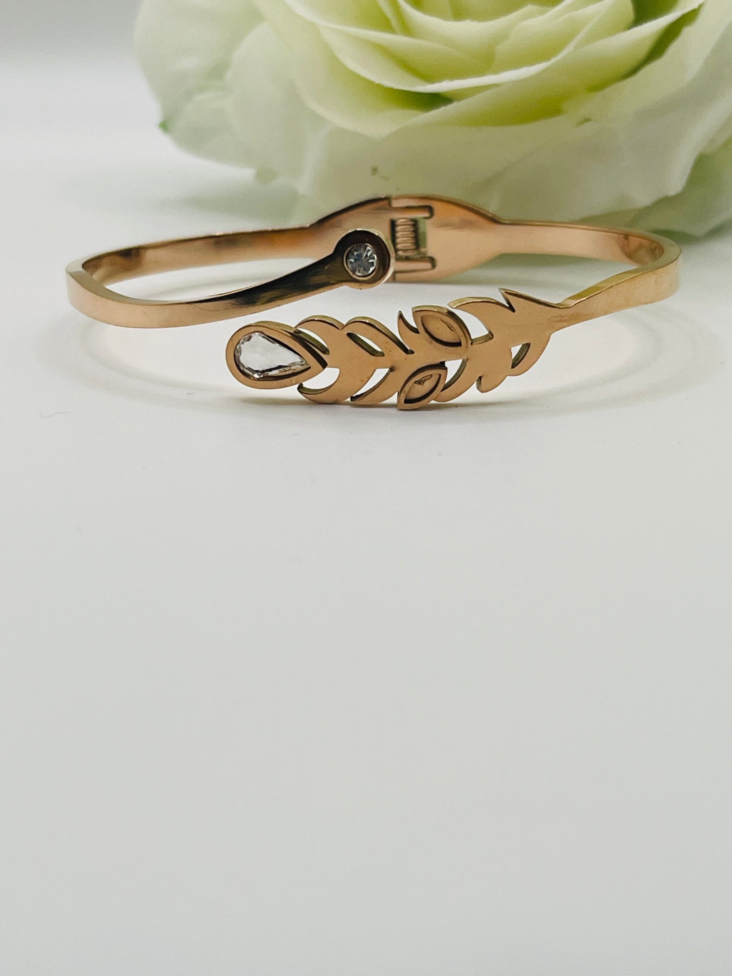 Rose gold bracelet with leaf design on a light gray background
