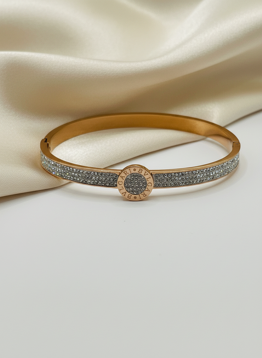 Rose Gold bracelet/bangle with diamond accents on a beige fabric background