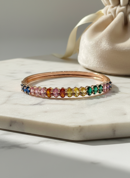 Multicolored gemstone bracelet on a marble surface with a beige drawstring bag in the background.