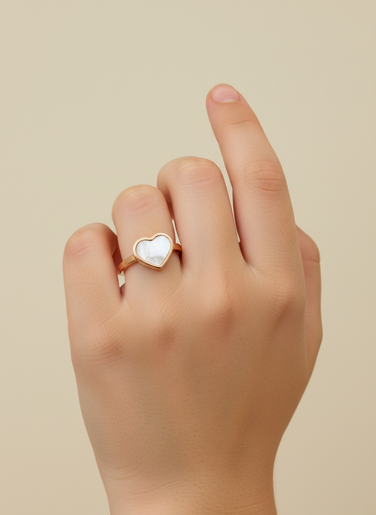 Gold heart-shaped ring on a white surface
