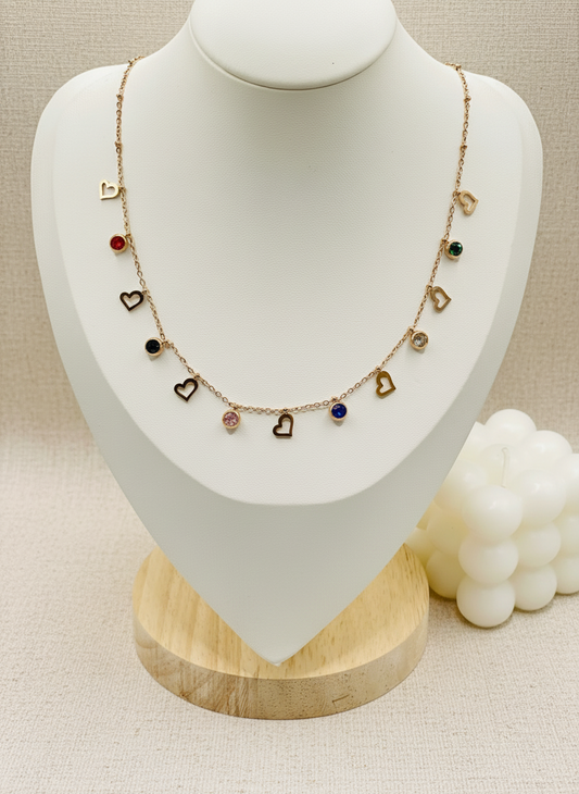 Necklace with heart-shaped charms on a mannequin bust with a ring beside it.