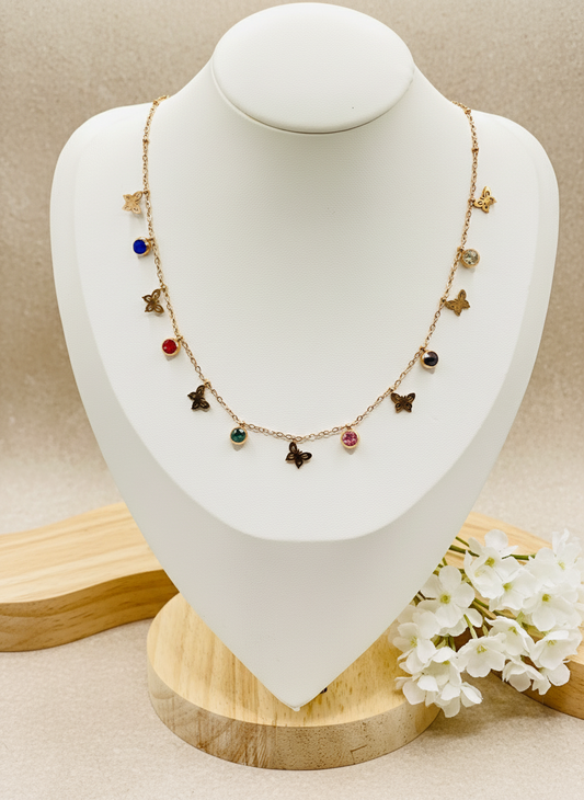 Necklace with colorful charms on a mannequin bust, accompanied by a ring on a small stand.