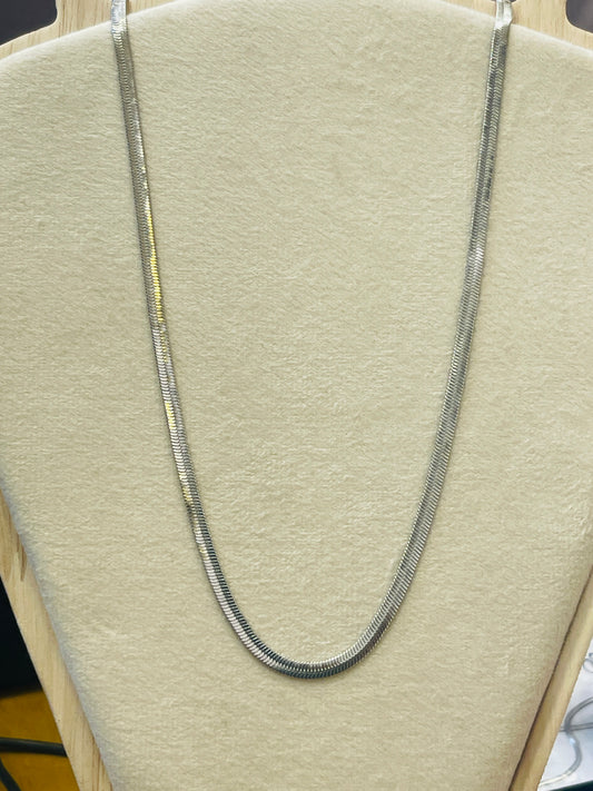 A silver-toned snake chain necklace draped over a beige fabric jewelry display bust.