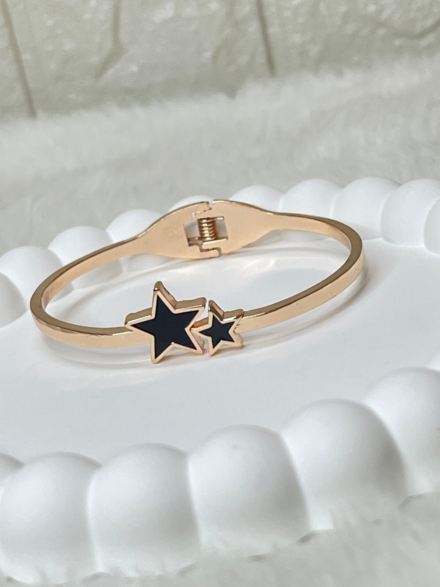 Rose Gold ring with a black star design on a textured white surface