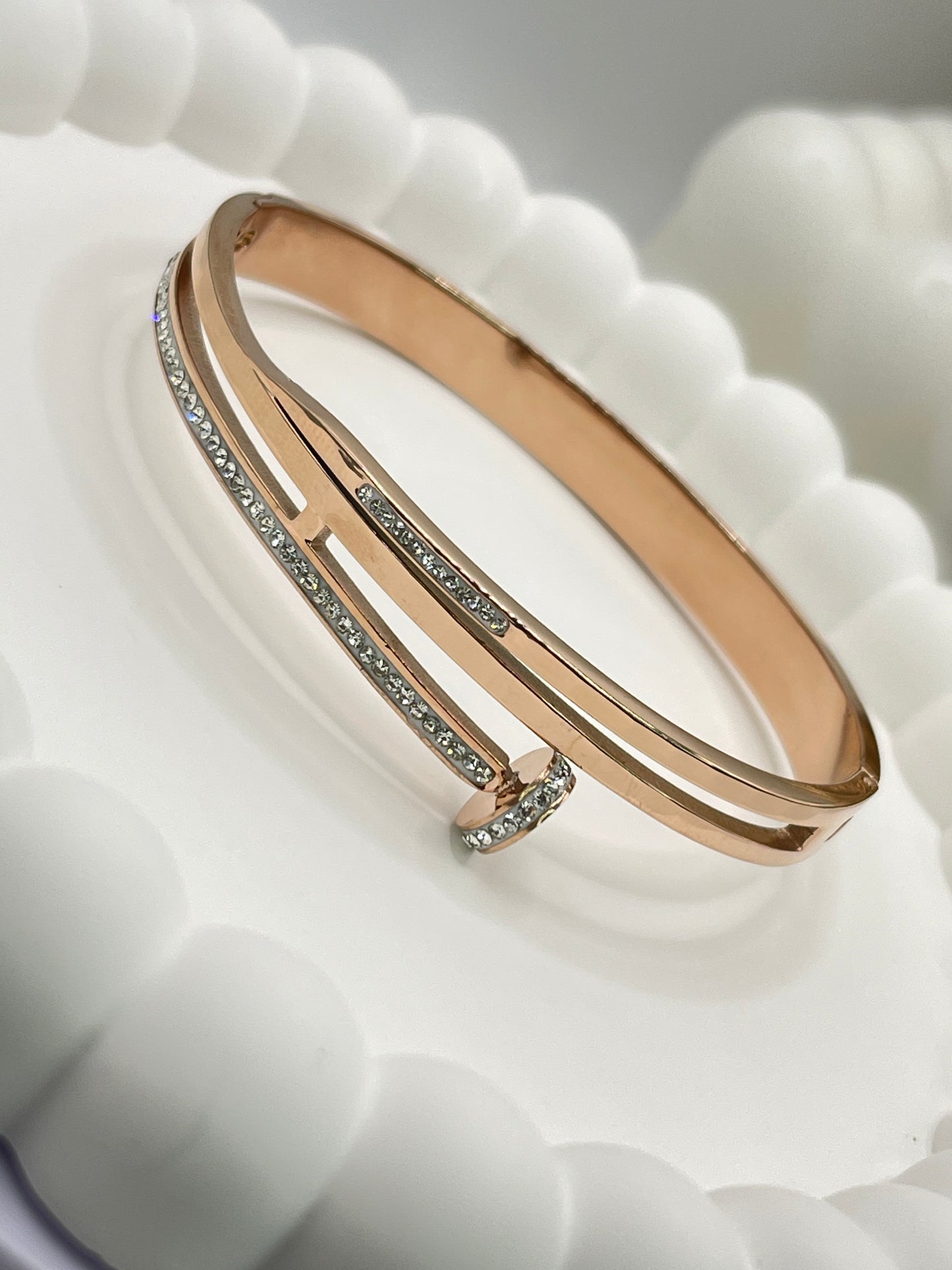 Rose gold bracelet with small diamonds on a textured white surface