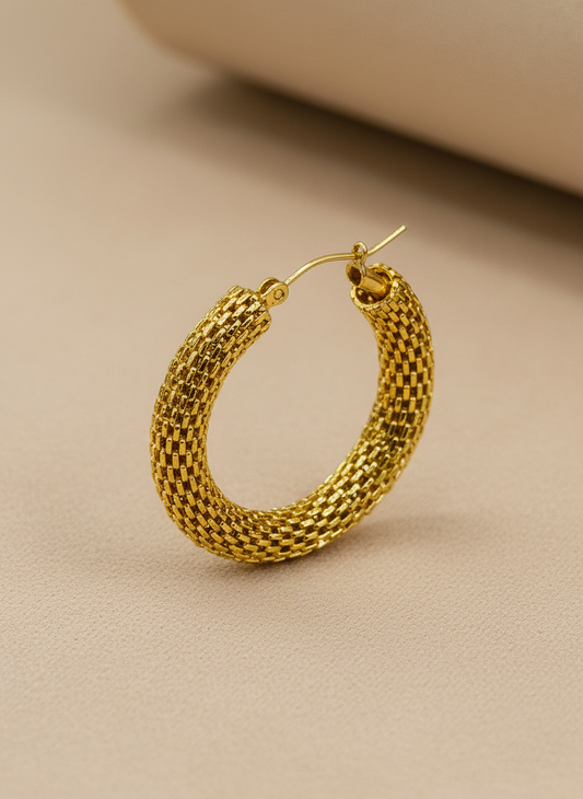 Gold hoop earrings on a white surface with a floral background