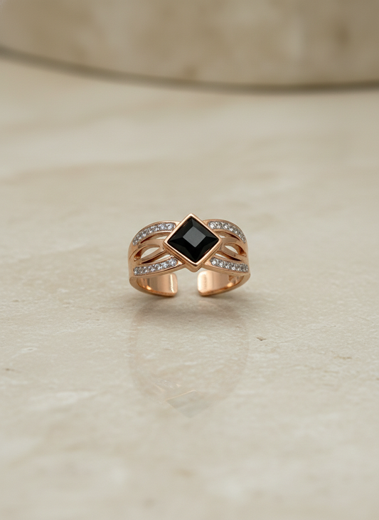 Rose Gold ring with a black gemstone on a beige surface