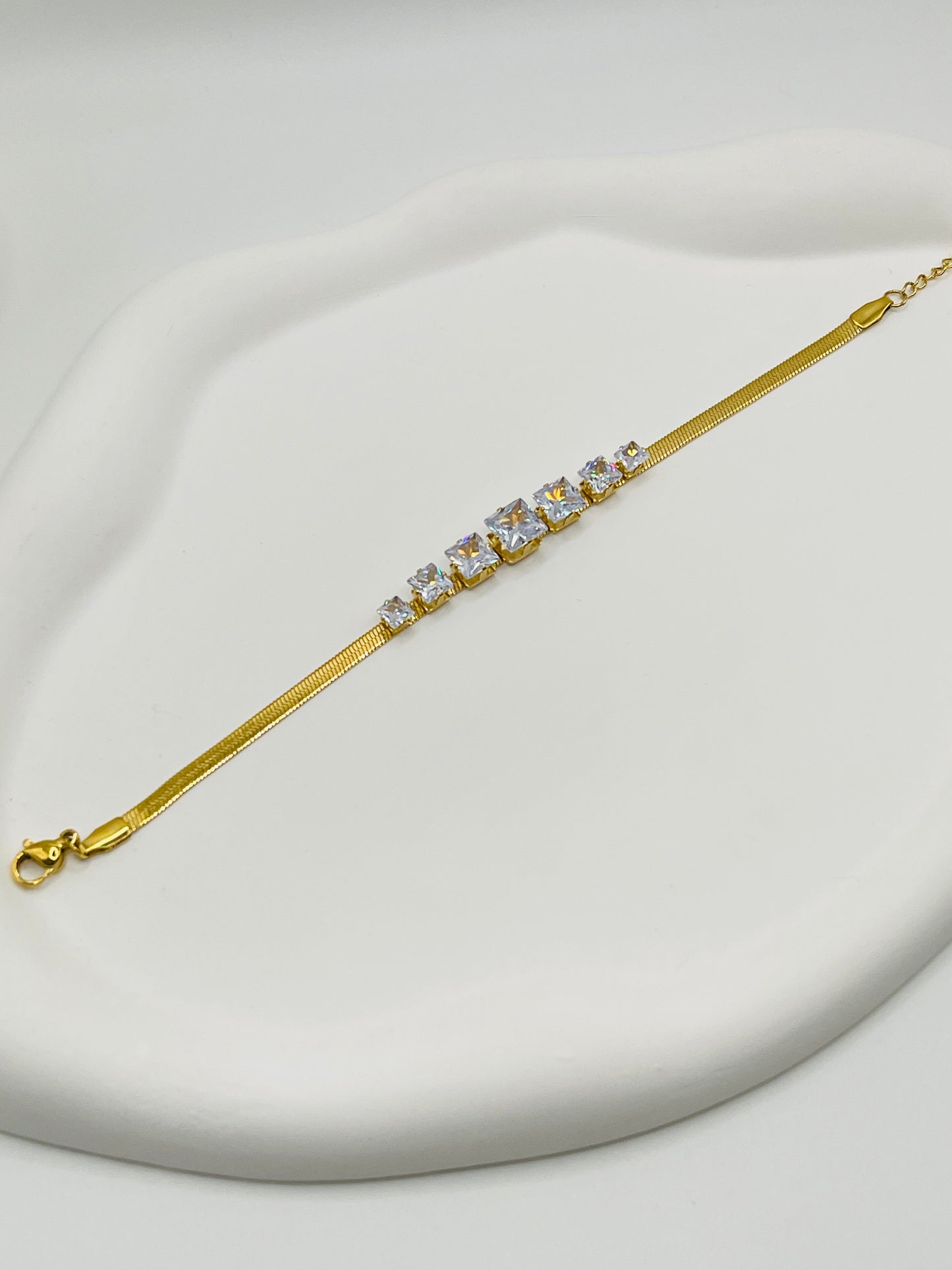 Gold bracelet with crystals on a light gray background