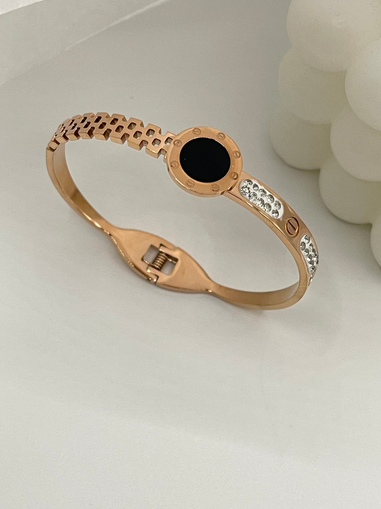 Rose gold bracelet with black center stone on a white background