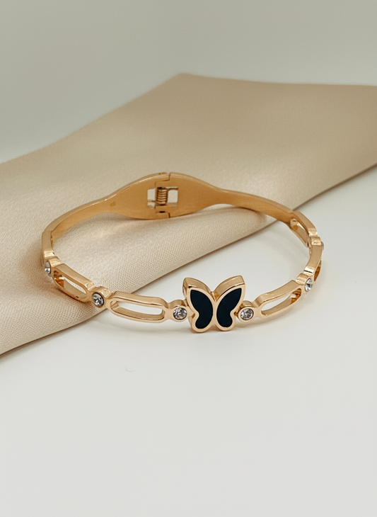 Rose Gold bracelet with a butterfly charm on a beige fabric background