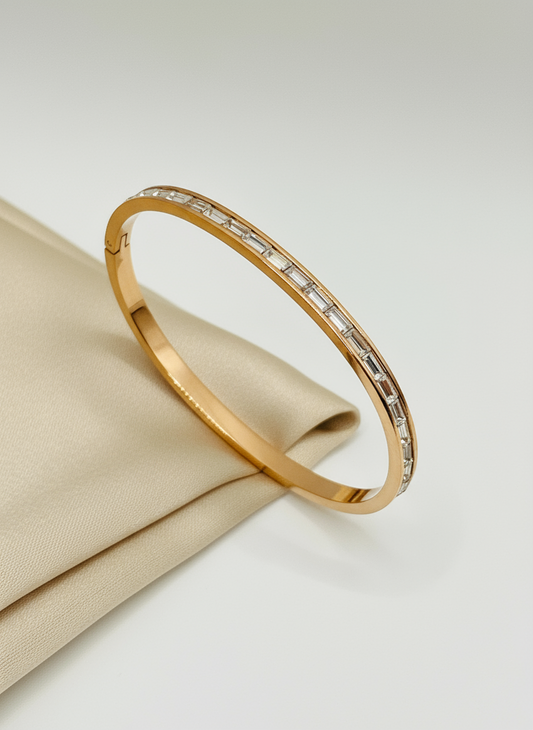 Rose Gold bracelet with embedded stones on a beige fabric background