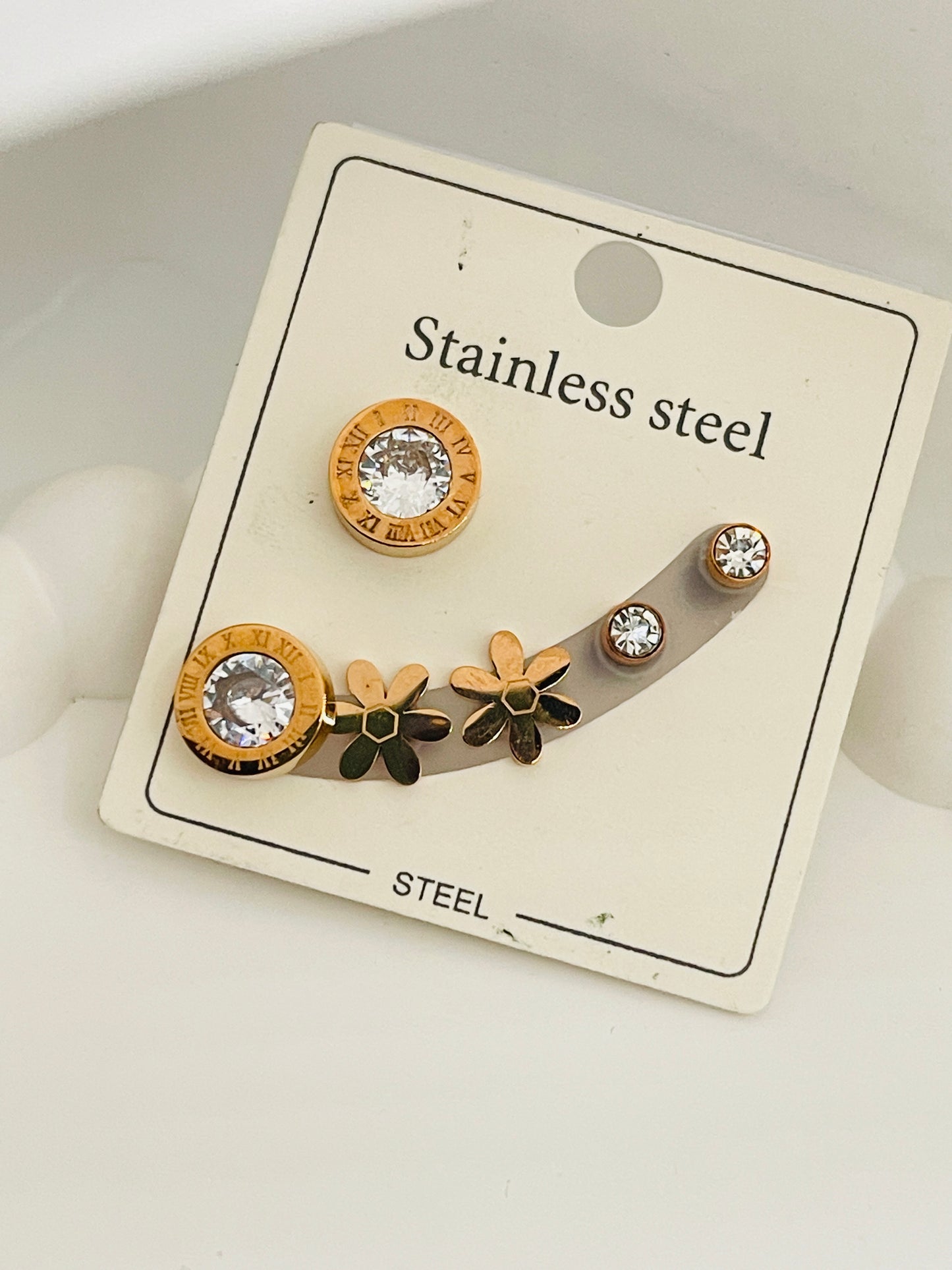 Set of stainless steel earrings on a display card with floral designs.