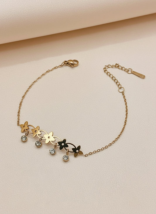 Rose gold bracelet with floral designs and small stones on a white surface.