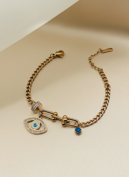 Rose Gold bracelet with eye charm and blue gemstone on a beige background