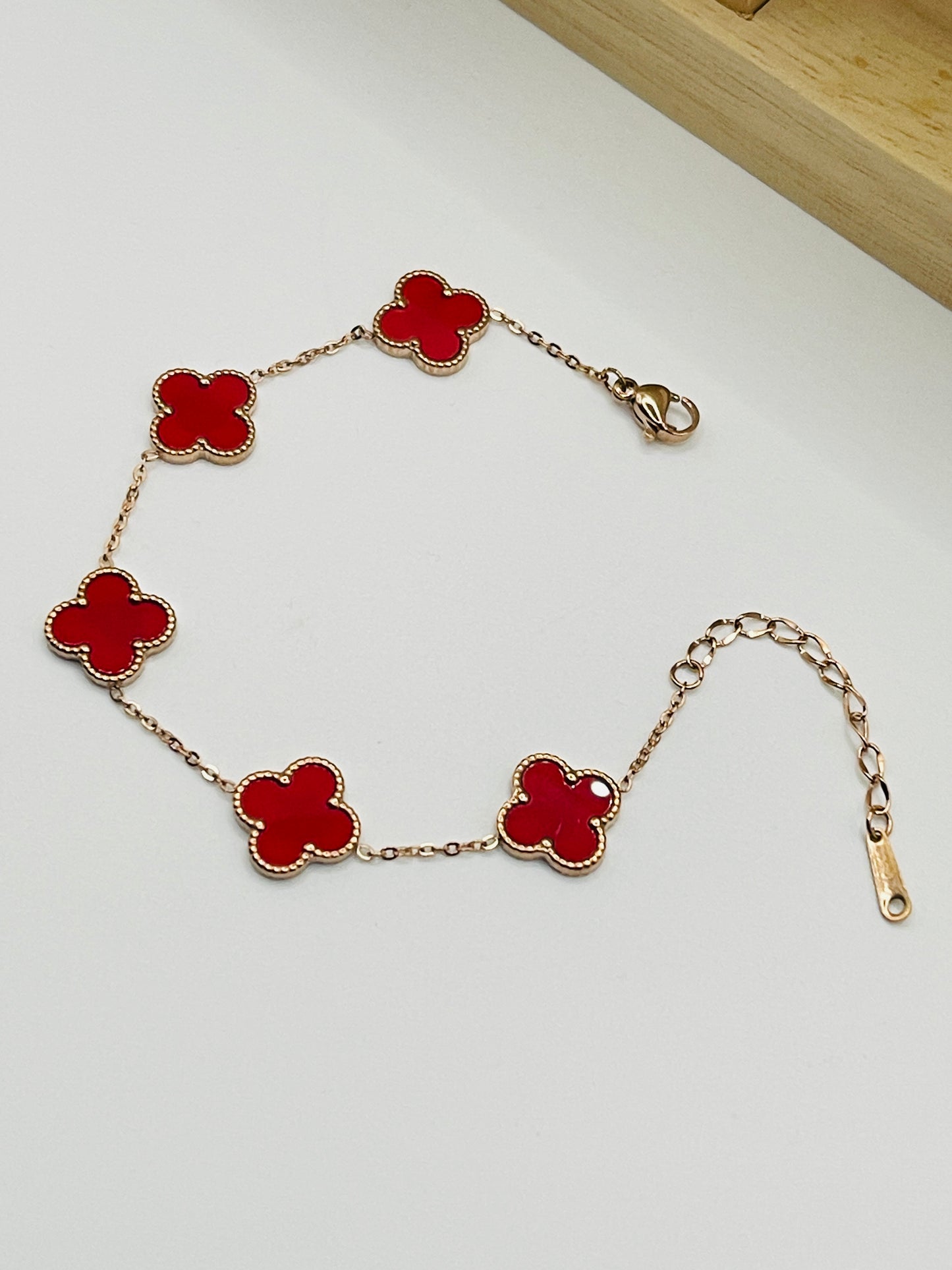 Rose Bracelet with red clover-shaped links on a white background