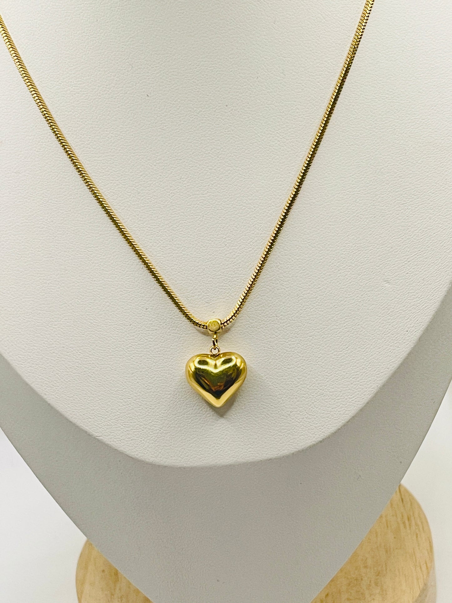 Gold heart-shaped pendant necklace on a mannequin bust.