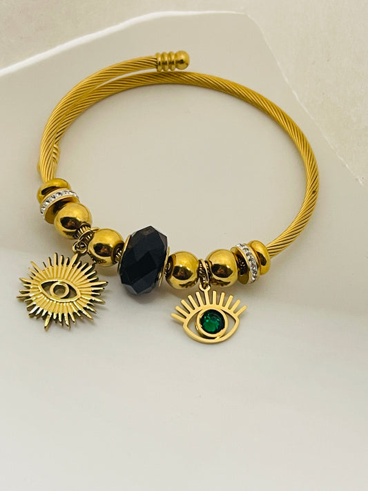 Gold bracelet with eye-shaped charms on a light gray background