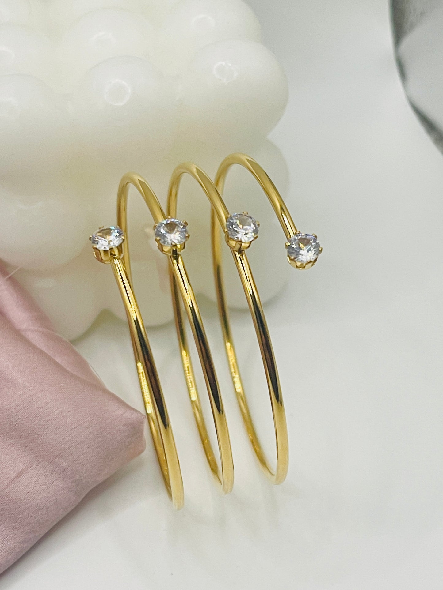 Gold hoop earrings with clear gemstones on a light background