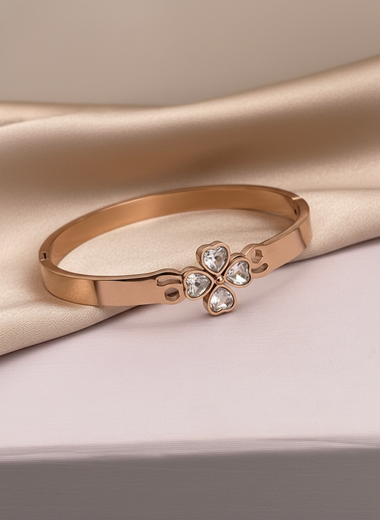 Rose gold bracelet with a floral clasp featuring clear stones on a beige fabric background