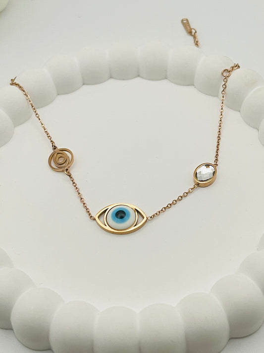 Rose gold bracelet with eye-shaped pendant on a white textured surface