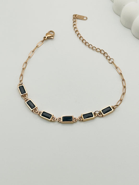 Rose Gold bracelet with black stones on a light gray background