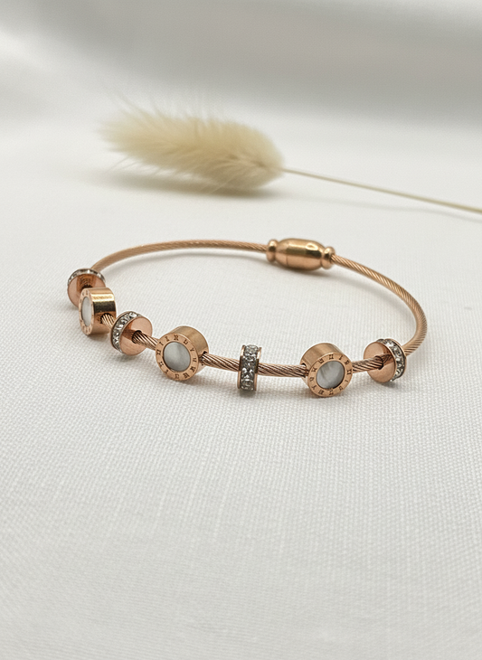 Rose gold bracelet with gemstones on a light background