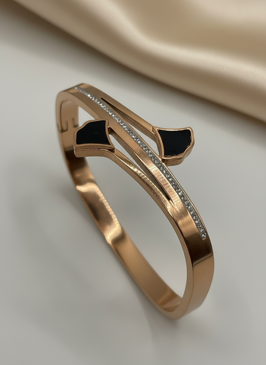 Rose gold bracelet with black stones on a beige background