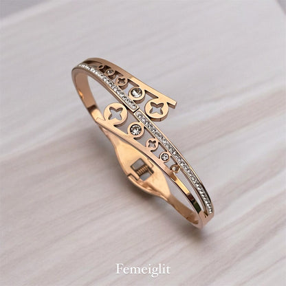 Rose gold bracelet with decorative elements on a light background, branded 'Femeiglit'.