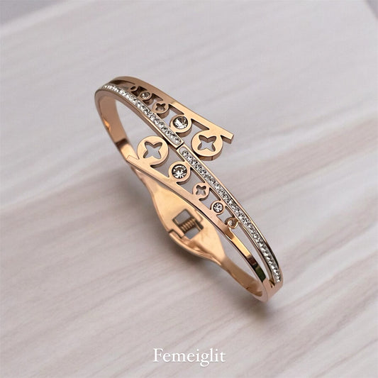 Rose gold bracelet with decorative elements on a light background, branded 'Femeiglit'.