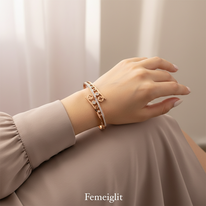 Hand wearing a gold bracelet with a neutral background, featuring the brand 'Femeiglit'.