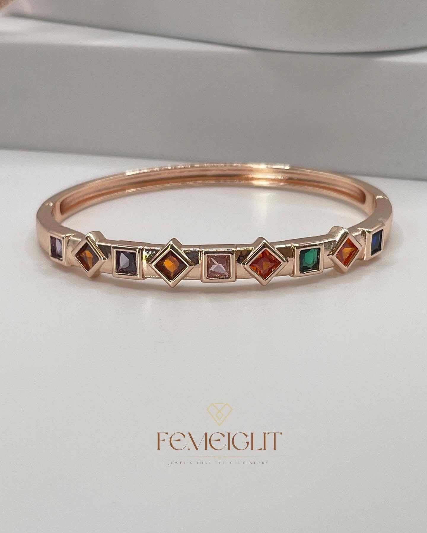 Rose gold bracelet with colorful gemstones on a white background, featuring the brand 'Femeiglit'.