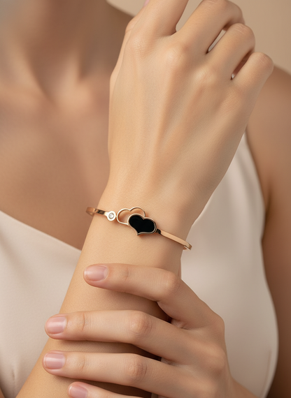 Rose gold bracelet with a heart-shaped black stone on a light gray background, featuring the brand 'FEMEIGLIT'.