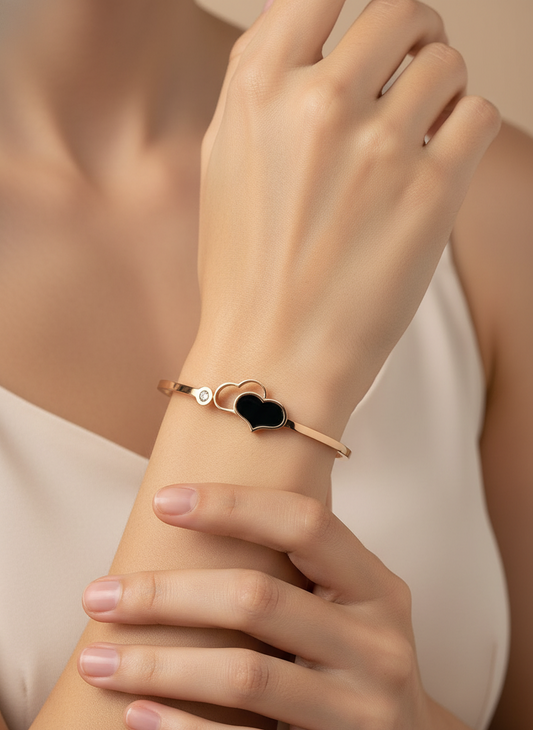 Rose gold bracelet with a heart-shaped black stone on a light gray background, featuring the brand 'FEMEIGLIT'.