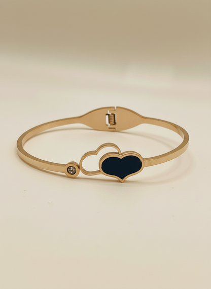Rose gold bracelet with a heart-shaped black stone on a light gray background, featuring the brand 'FEMEIGLIT'.