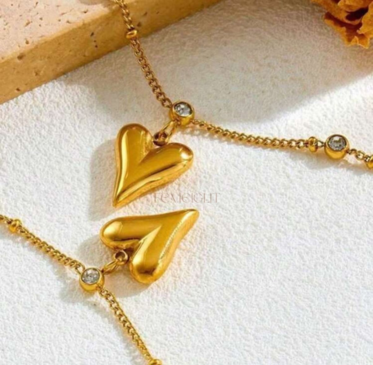 Gold necklace with heart-shaped pendants on a white surface
