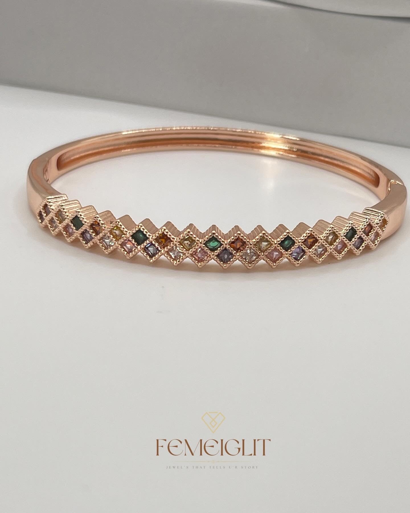 Rose gold bracelet with embedded gemstones on a light background, featuring the brand 'FEMEIGLIT'.