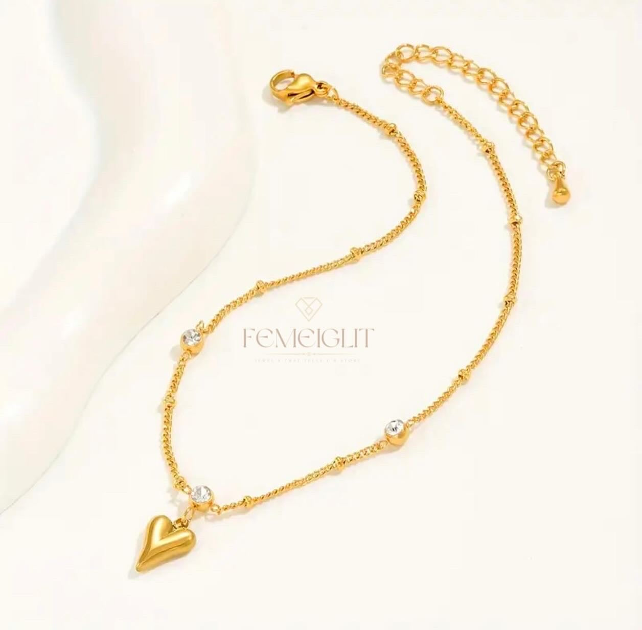 Gold necklace with heart pendants on a light background, featuring the brand 'FENNEIGIT'.