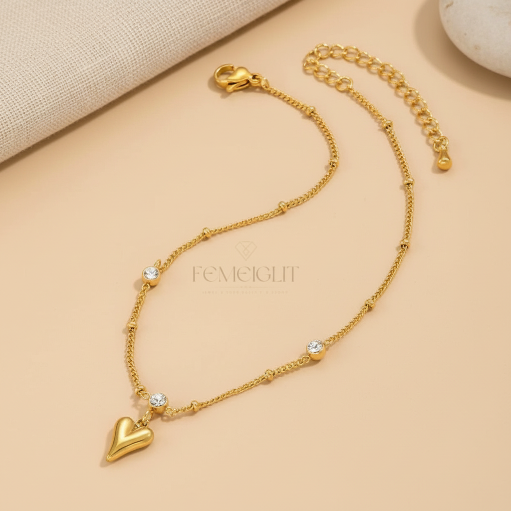 Gold heart-shaped bracelet with small crystals on a beige background