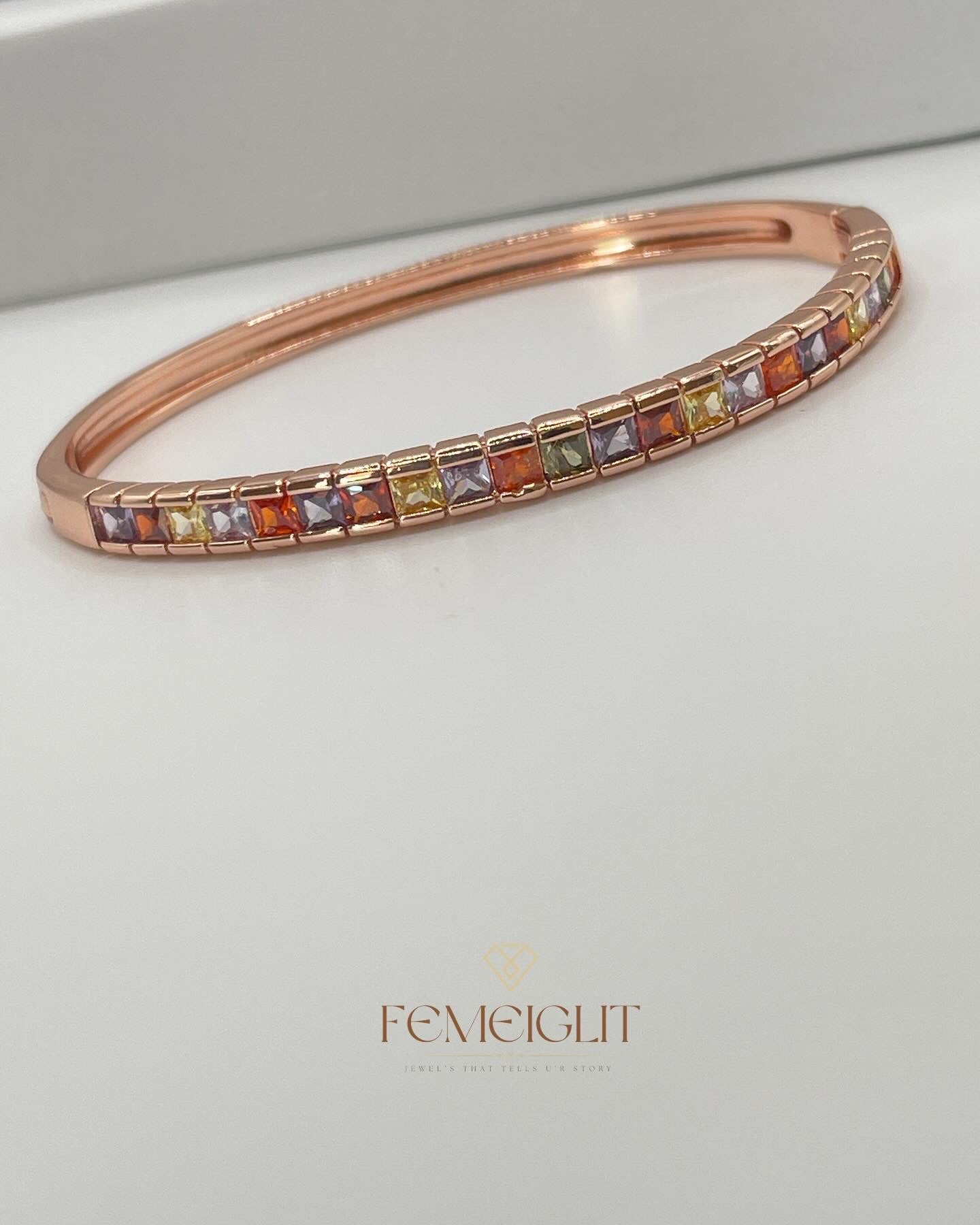 Rose gold bracelet with multicolored gemstones on a light gray background, featuring the brand 'Femeiglit'.