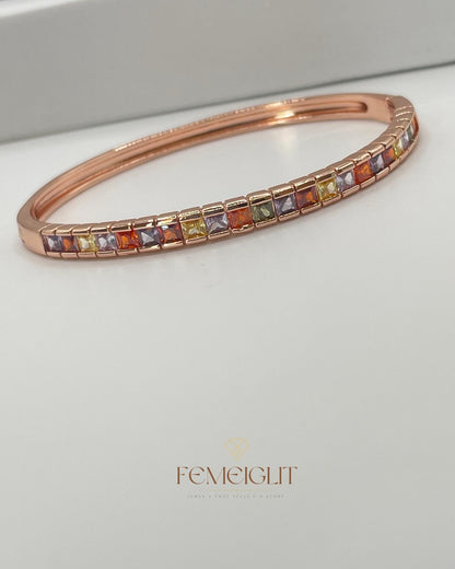 Rose gold bracelet with multicolored gemstones on a light gray background, featuring the brand 'Femeiglit'.