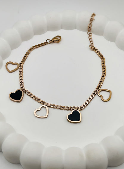 Rose Gold bracelet with heart-shaped charms on a white textured surface