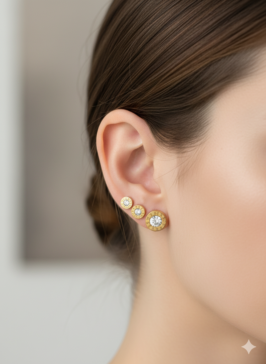 Close-up of a person wearing rose gold earrings with gemstones on a neutral background