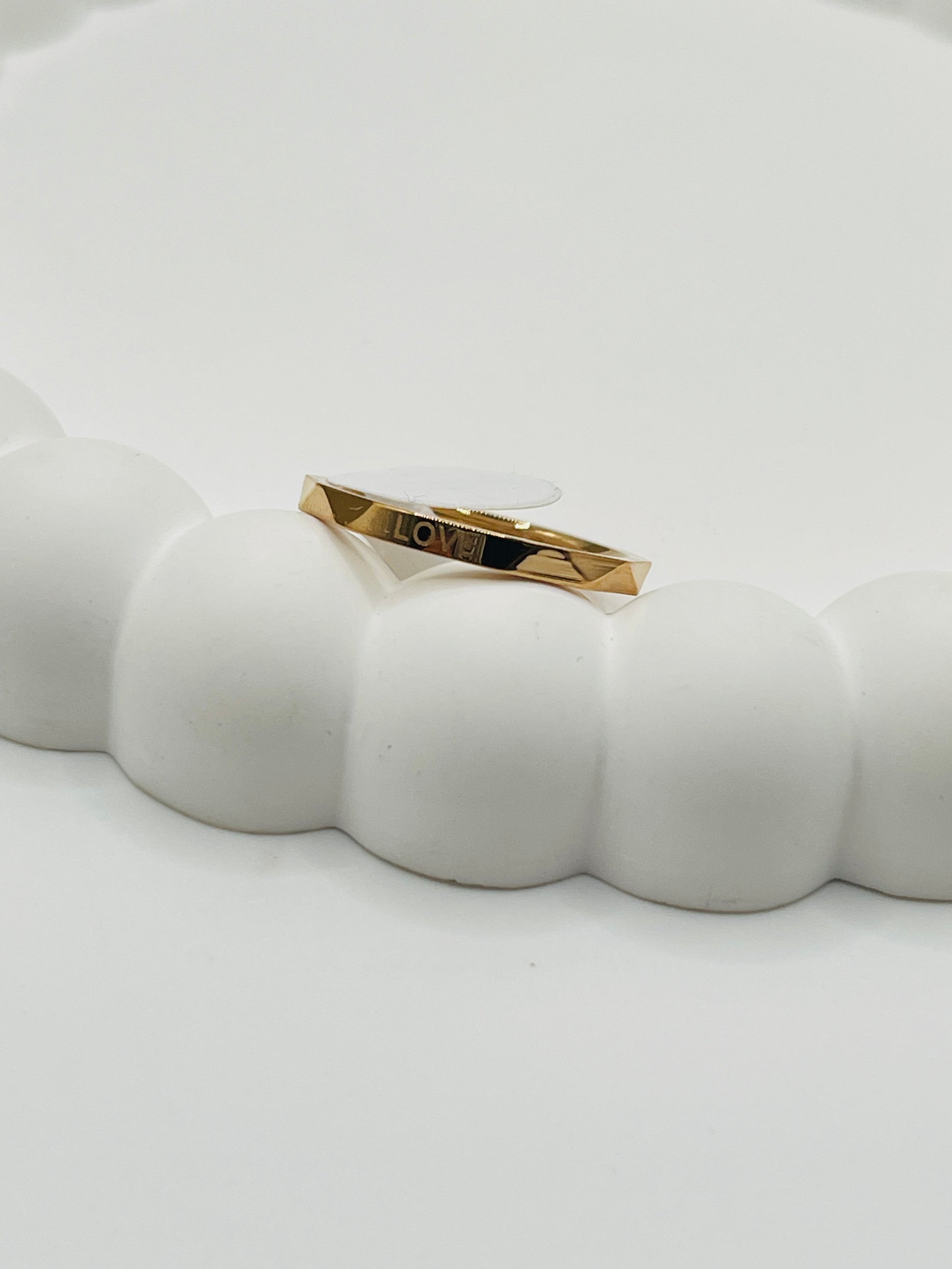 Rose Gold bracelet with 'LOVE' engraving on a white ceramic dish