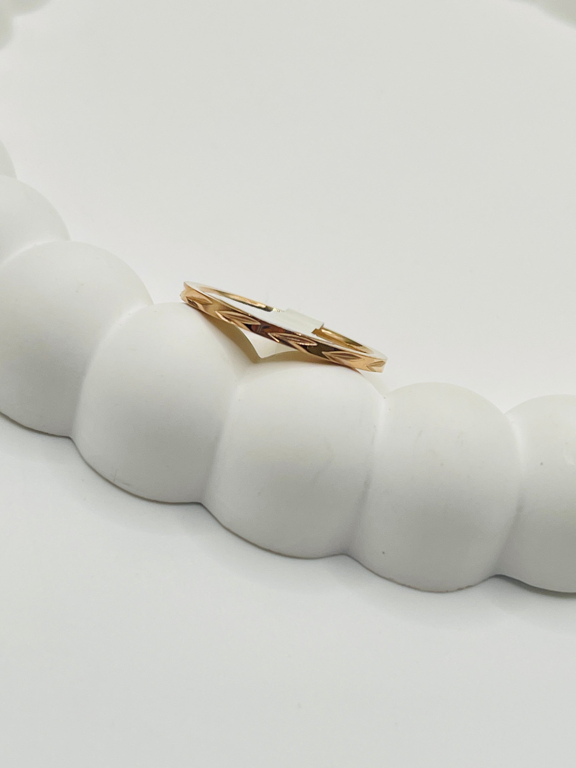 Rose Gold ring with a white stone on a textured white surface