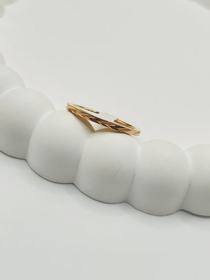 Rose Gold ring with a white stone on a textured white surface